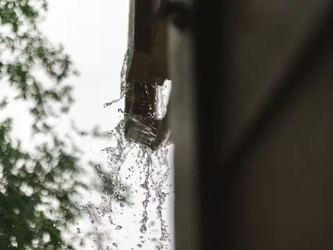 Rainwater spilling from a gutter in a downpour