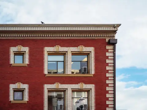 A red brick corner building with a white cornice and stone trim