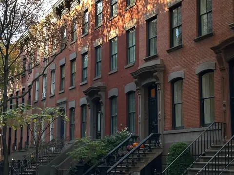 A row of attached brick rowhouses with stoops and no side yards