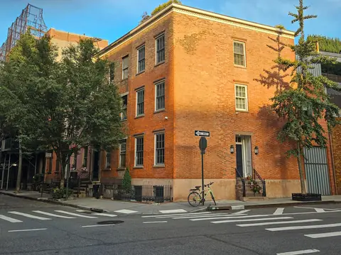 A brick corner building with a cornice in afternoon sun