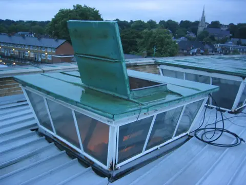 A roof hatch propped open on a flat roof