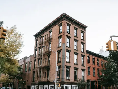 A brick corner building with a cornice on a city street