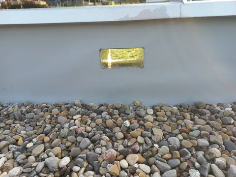 A scupper opening through the parapet of a gravel flat roof