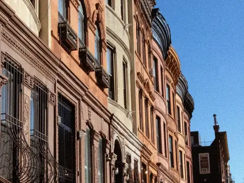 A row of brownstone cornices against a blue sky