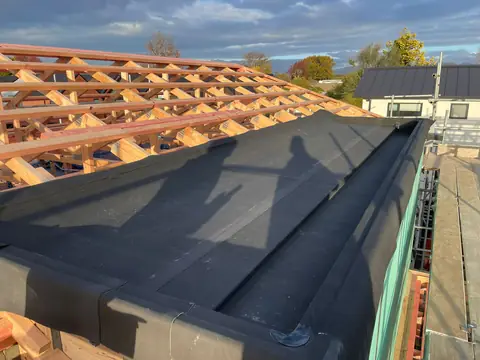 A rubber membrane turned up the side of a roof edge during new roofing work