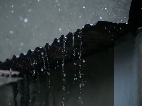 Rainwater dripping off the edge of a roof