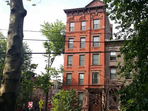 A brick building with a carved cornice beside Van Vorst Park in Jersey City