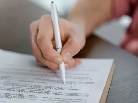 A hand signing a written contract at a table